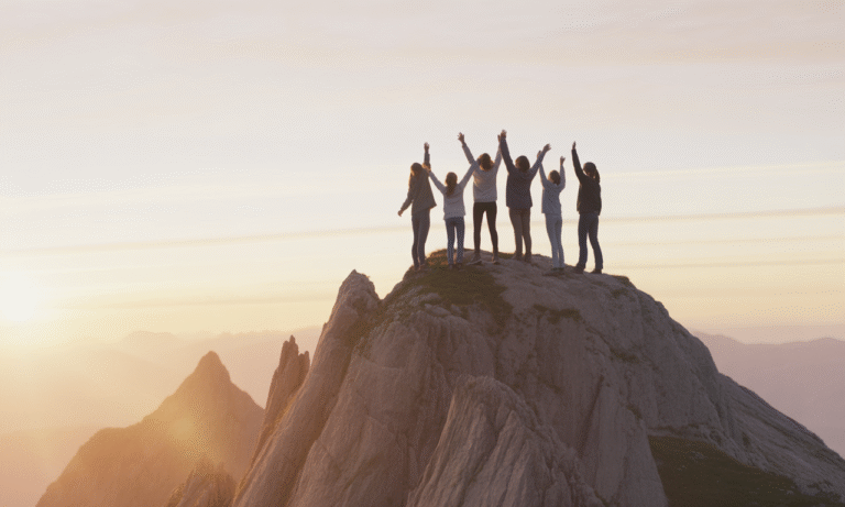 Women raising their arms on a mountaintop at sunrise, symbolizing resilience, confidence, and self-trust for woman entrepreneurs.